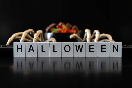 Skeleton hands on keyboard with bowl of Halloween candies