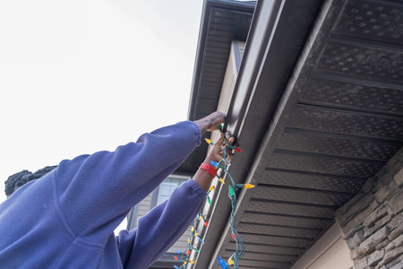 African American Nigerian Woman installing christmas lightsの写真素材