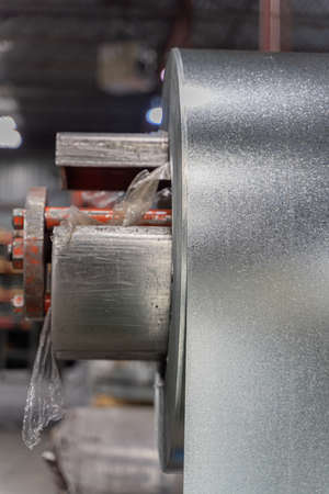 roll of silver metal steel coil in a metal roofing factoryの写真素材