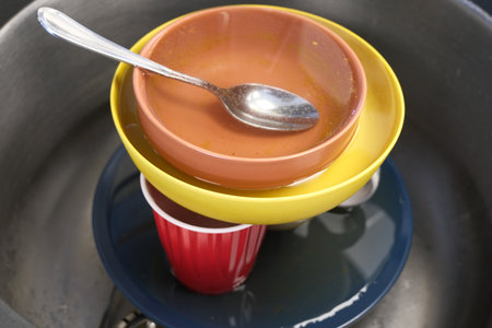 Stack of plates and bowls in sink for washingの写真素材