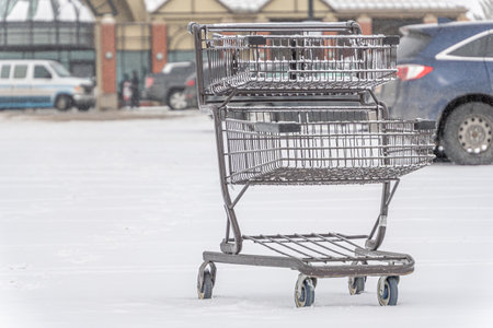 shopping cart in snow covered grocery store parking lotの写真素材