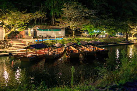 River tour boats sit idle along river in Kyoto at night