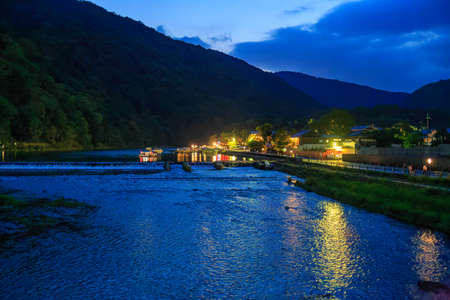 Blue hour over river through mountains with cafe lights on shoreの写真素材
