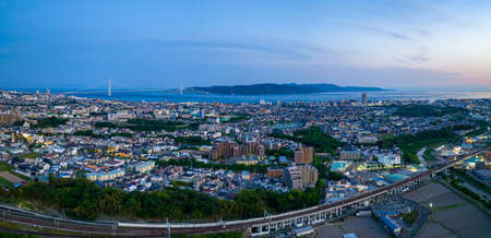 Panoramic aerial view of Akashi City and Awaji Island with bridge in distance at blue hour