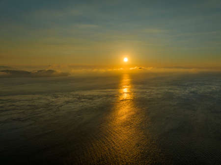 Low sun shines through clouds and reflects off open ocean at dawnの写真素材
