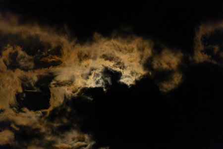 Full moon lights dark clouds in night sky
