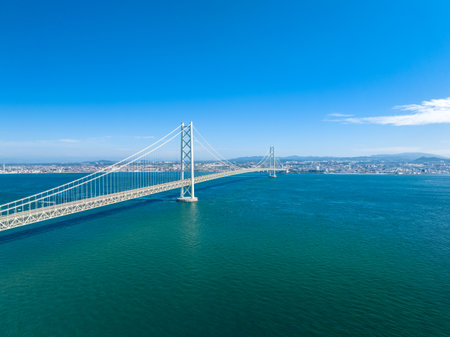 Long suspension bridge over calm water on sunny blue sky dayの写真素材