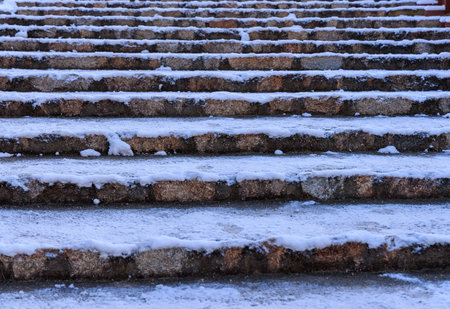 Ancient stone steps covered with slippery snow and ice after winter stormの写真素材