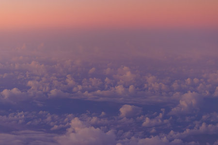 Pink glow on horizon over clouds and blue ocean at sunrise