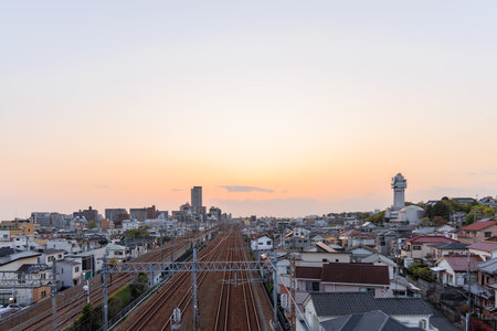 Akashi, Japan - April 19, 2023: Sunset on train tracks through neighborhood by clock towerのeditorial素材