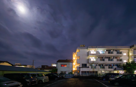 Moon light over apartment building in quiet neighborhood at nightの写真素材