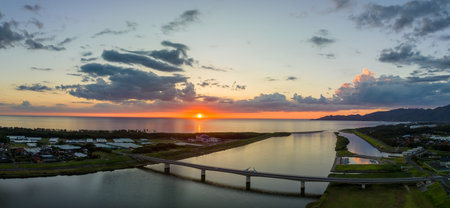 Sunset on horizon over Sea of Japan by coastal river and bridgeの写真素材