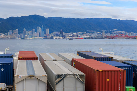 Kobe, Japan - September 23, 2023: Shipping containers on ship in coastal waters near city and...