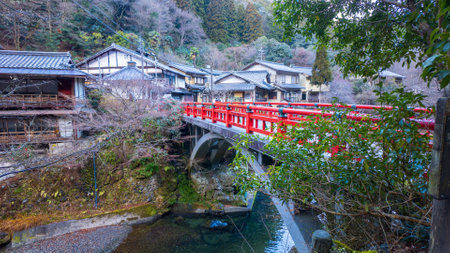 Red bridge over small river by traditional Japanese villageの写真素材