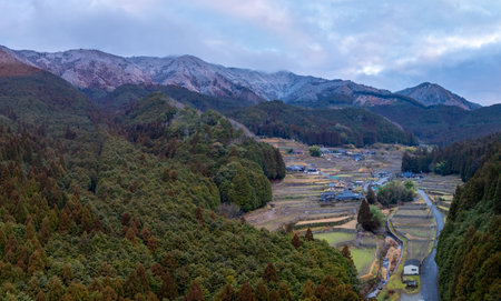 Aerial view of traditional farming village by snow covered mountains of Japanの写真素材