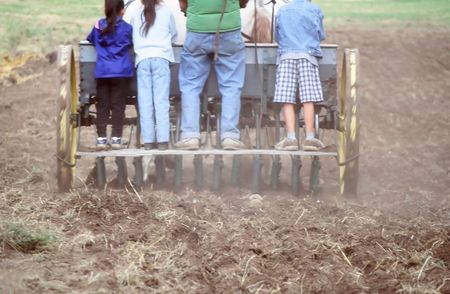 Kids riding a wagon plow with the farmer.の写真素材