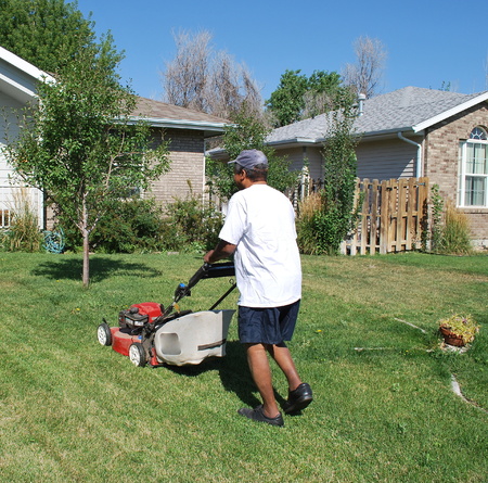 African american male mowing the lawn outside.の写真素材