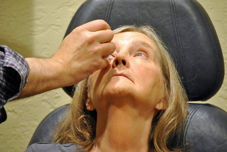 Mature female having an eye exam inside a clinic.の写真素材