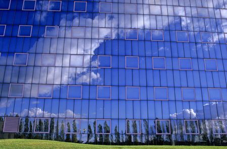 reflection of the sky in the windows of a mirrored office buildingの写真素材