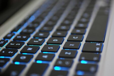 Laptop keyboard with blue backlight. Buttons closeup showing black details, white letters and silver body - Closeup Viewの写真素材