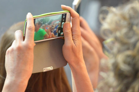 Barcelona, Spain - July 5, 2014  A woman between the public taking a picture with your smart phone for some athletes holding a street race in Barcelona, Spain のeditorial素材