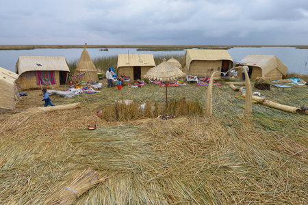 PUNO LAKE TITICACA, PERU - SEPTEMBER 5: Local people in traditional attires welcome tourists coming by boats at Uros Islands on September 5, 2015 in Lake Titicaca, Peruのeditorial素材