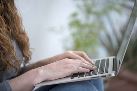 Close up of a woman hands working with a laptop at home.の写真素材