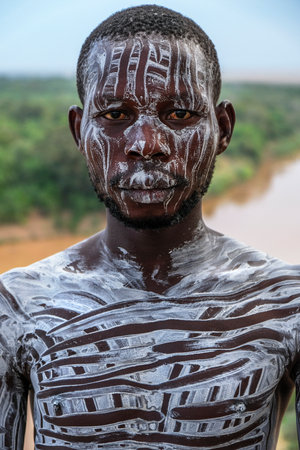Omo Valley, Ethiopia - January 26: Unidentified Karo Man with Omo River in the background on January 26, 2018 in Omo Valley, Ethiopia. Karo tribes are famous for their body painting.のeditorial素材