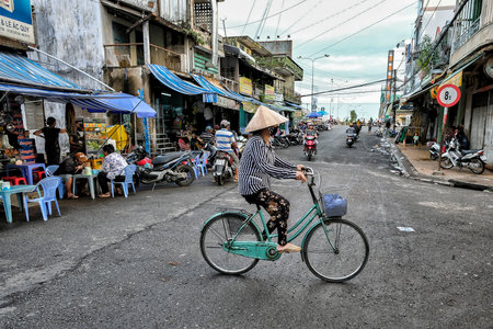 My Tho, Vietnam - August 9: A woman wearing a traditional non conical hat riding a bicycle on August 9, 2018 in My Tho, Vietnam.のeditorial素材