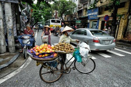 Hanoi, Vietnam - August 29: Vietnamese women selling tropical fruits on the street with her bicycle on August 29, 2018 in Hanoi.のeditorial素材