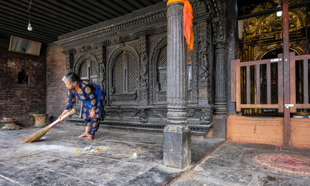 Bhaktapur, Nepal - October 2021: A woman cleaning at the Dattatreya Temple in Bhaktapur on October 9, 2021 in Kathmandu Valley, Nepal.のeditorial素材
