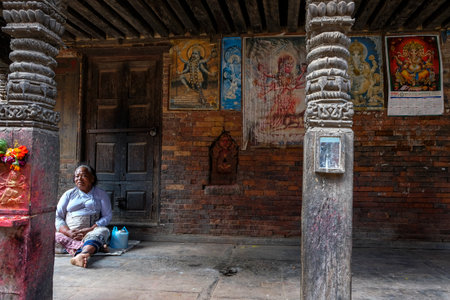 Bhaktapur, Nepal - October 2021: A woman rests seated next to images of Hindu gods in Bhaktapur on October 9, 2021 in Kathmandu Valley, Nepal.のeditorial素材