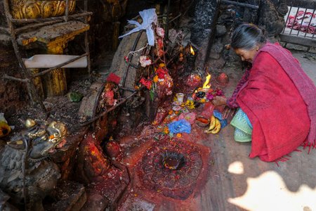 Bhaktapur, Nepal - October 2021: A woman making an offering at a Hindu temple in Bhaktapur on October 9, 2021 in Kathmandu Valley, Nepal.のeditorial素材