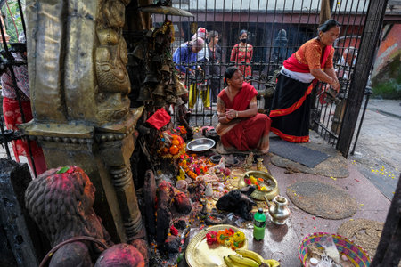 Bhaktapur, Nepal - October 2021: Women making an offering at the Mahakali Temple in Bhaktapur on October 9, 2021 in Kathmandu Valley, Nepal.のeditorial素材