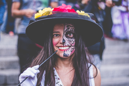 Foreign woman in Mexico City with half her face made up of catrina, smoking cigarette during the...