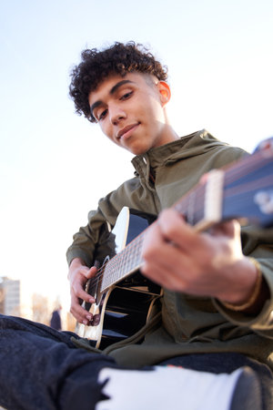 latin teenager concentrating on playing guitarの写真素材
