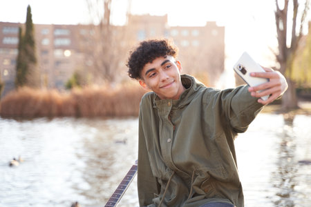 young teenager taking a selfie with smartphone in a city parkの写真素材