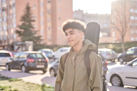 portrait of young teenager man posing outdoor with his guitar gig bag, model is Latin American Ethnic.の写真素材