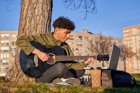 self-taught young man playing and learning to play the guitar with the laptop. teenager composing a song.の写真素材