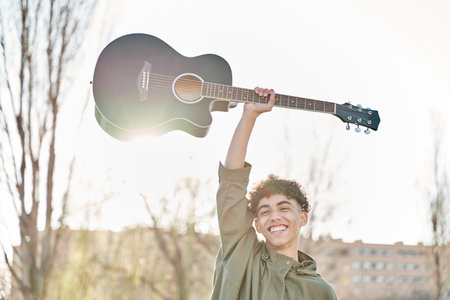 Man with happy face holding guitar above his head. Concept of rock musician.の写真素材