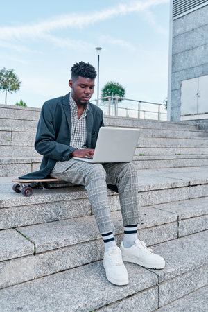 Portrait of african american handsome man in casual wear sitting using laptop for online meeting, video call, video conference. Online communication with colleagues. Online education, remote working.の写真素材