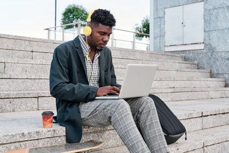 young African-American man in the city making a video call or working on the laptop with headphones onの写真素材