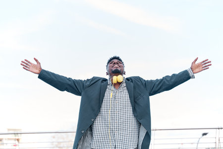 man smiling arms raised up to blue sky, celebrating freedom. Positive human emotions, face...