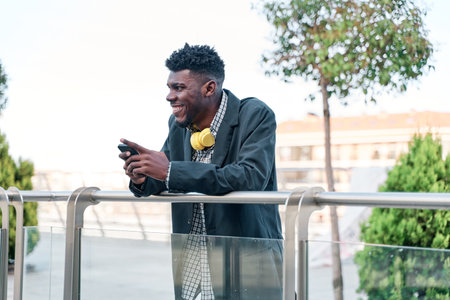 Happy african american man using mobile phone on streetの写真素材