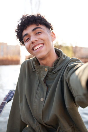young teenager taking a selfie with smartphone in a city parkの写真素材