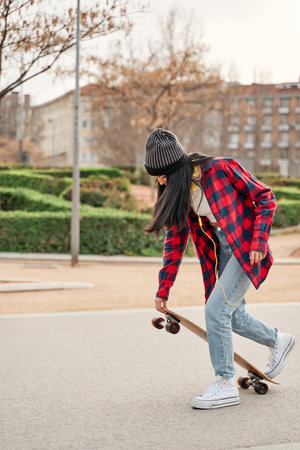 Latina woman in casual clothes skateboarding in the cityの写真素材