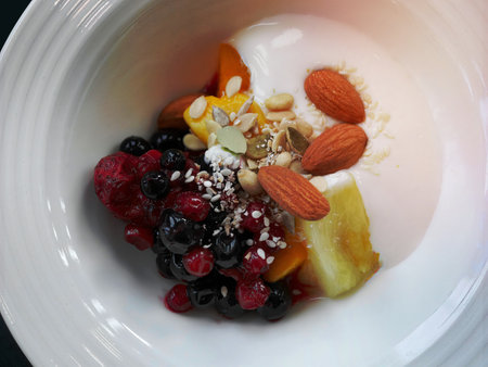 close-up  of  top view vibrant color fresh mixed berries almond nuts and fruits with greek yoghurt...
