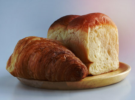 Close up, side view of a Plain croissant and Japanese soft and fluffy milk bread bun on a wooden...