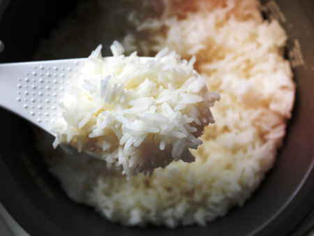 top view close-up of cooked jasmine white rice in the white ladle with background of electric rice cookerの写真素材