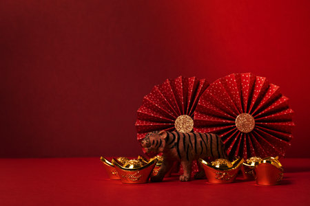 Chinese new year festival decoration over red background. traditional lunar new year gold ingots, paper fans, tiger. Copy spaceの写真素材